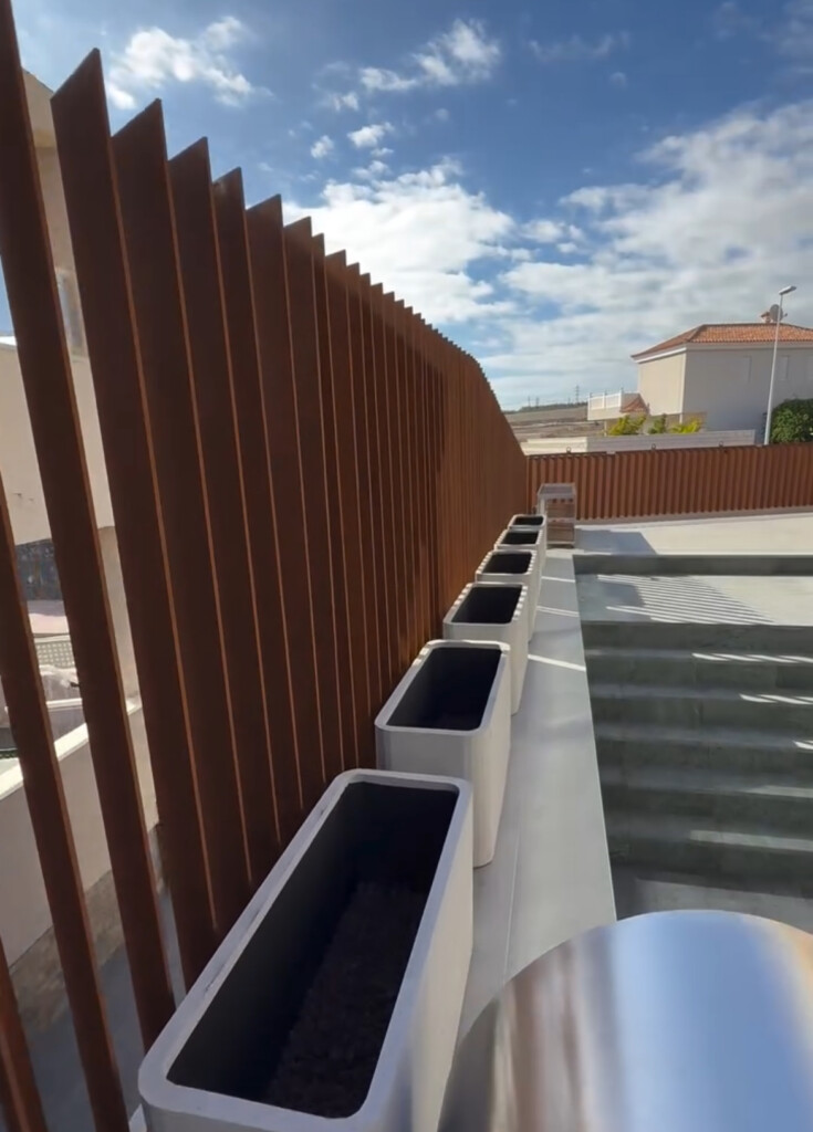 Паркан із сталі Corten B на Тенеріфе Деталь паркану з кортену крупним планом Виробництво паркану з кортену у Львові Піскоструминна очистка й патинування кортену на заводі Транспортування паркану зі Львова до Тенеріфе Текстура кортену — патина й природні зміни Готовий паркан з кортену у приватній резиденції на Тенеріфе
